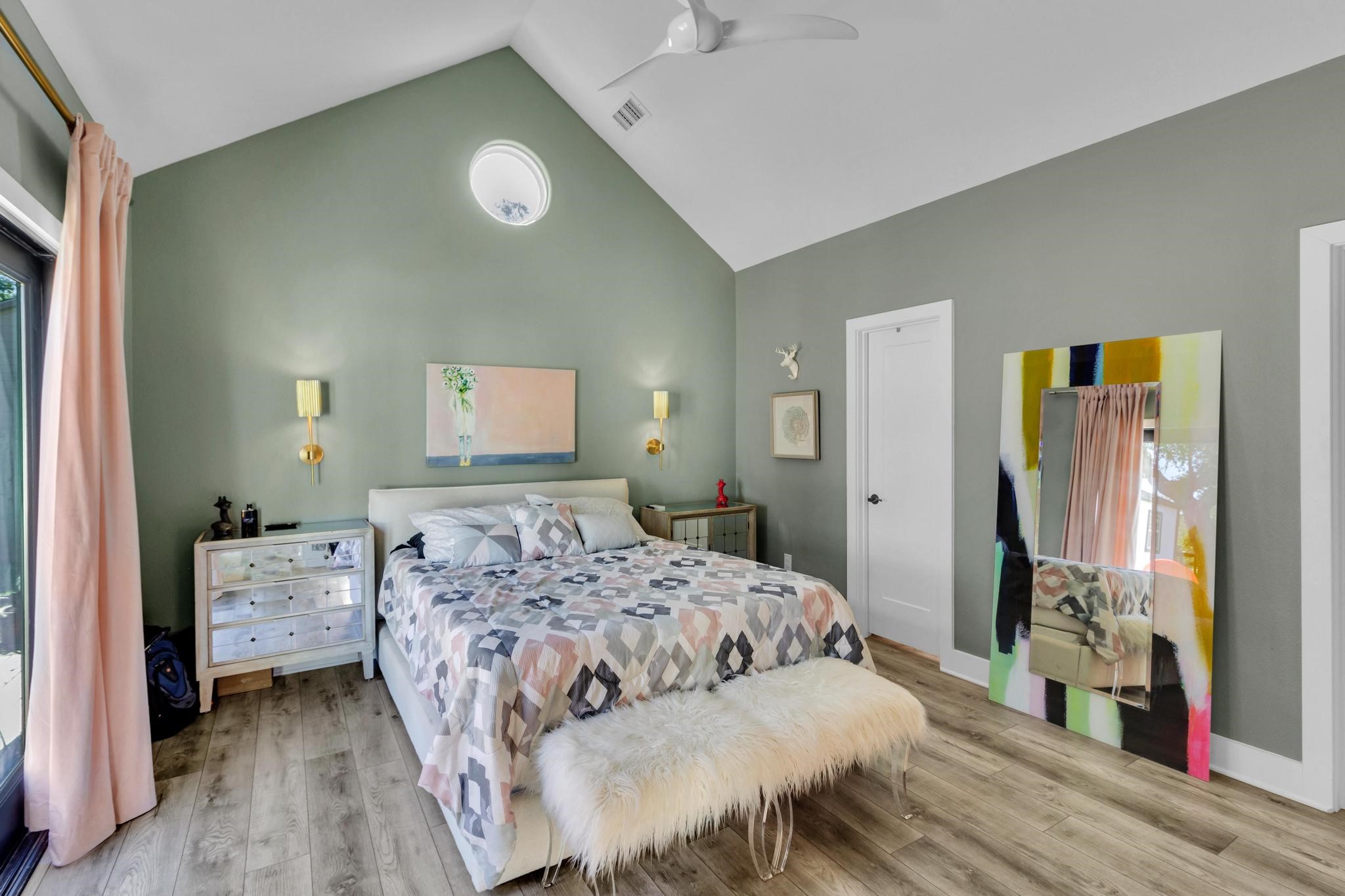295 County Road 687 Angleton, TX 77515 - Photo 30 of 38 This bedroom features a high vaulted ceiling and modern decor. The room is brightened by natural light from a large window with soft drapes, complemented by a minimalist ceiling fan.