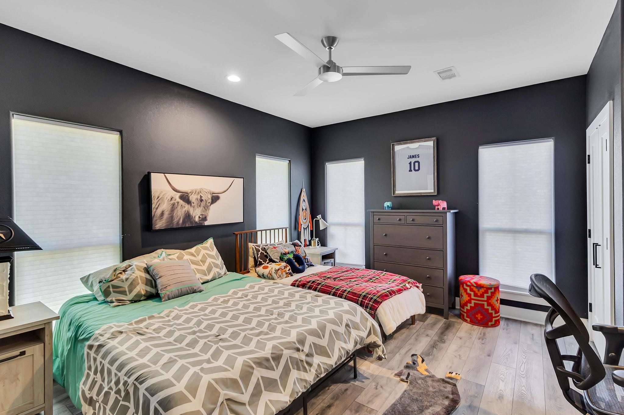 295 County Road 687 Angleton, TX 77515 - Photo 34 of 38 This cozy bedroom features a modern design with dark walls and light flooring. A modern ceiling fan is both artistic and functional.