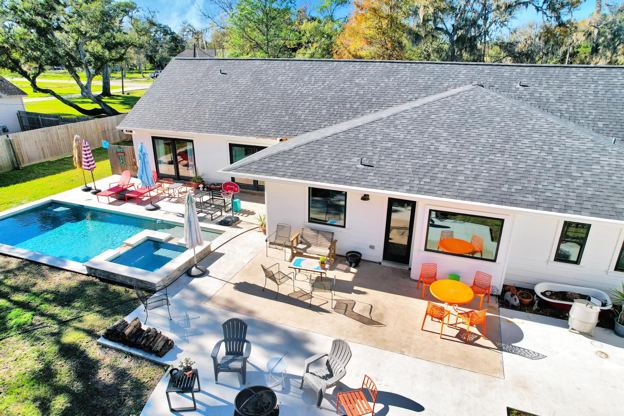 295 County Road 687 Angleton, TX 77515 - Photo 7 of 38 This photo showcases a modern backyard with a pool and patio area. The home features a spacious outdoor space with various seating options, perfect for entertaining. The pool includes a small spa, and the surrounding area is enhanced with colorful furniture and a well-maintained lawn, offering a relaxing and inviting atmosphere.