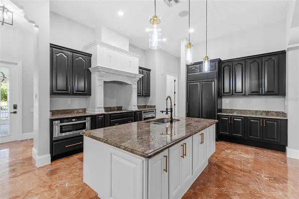 a view of a kitchen with a sink stainless steel appliances and a chandelier