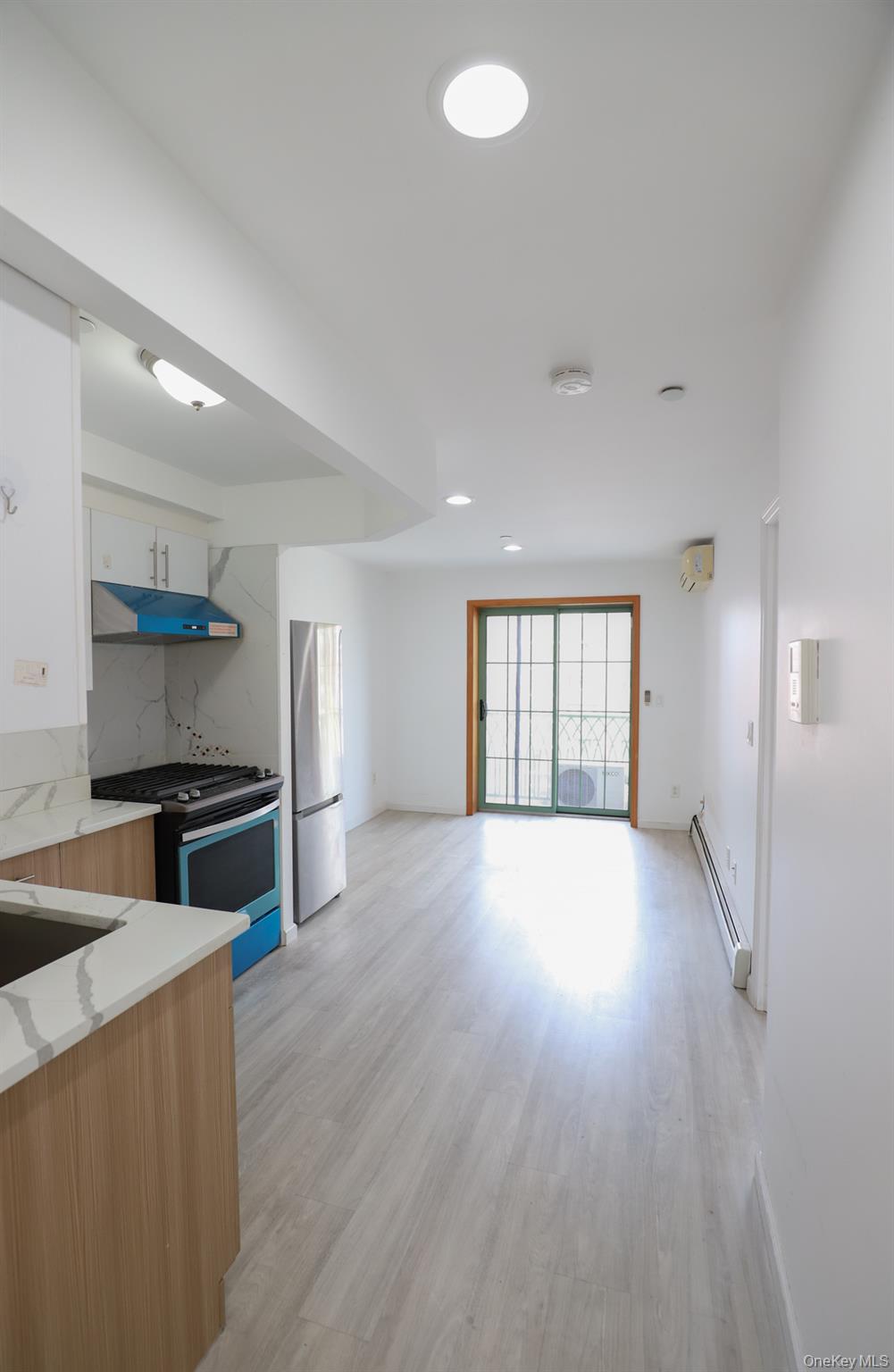 134-43 Maple Avenue, Unit 5B Queens, NY 11355 - Photo 4 of 13 a kitchen with a stove wooden floor and a window