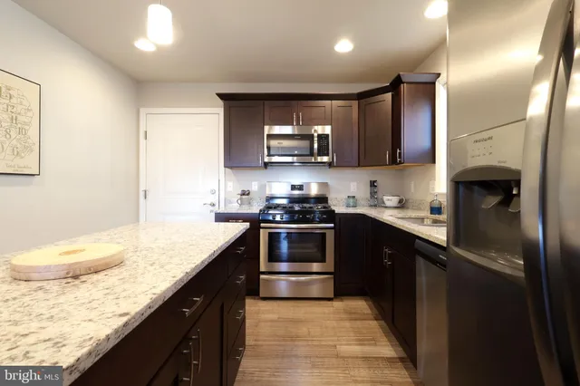 a kitchen with stainless steel appliances granite countertop a sink stove and refrigerator