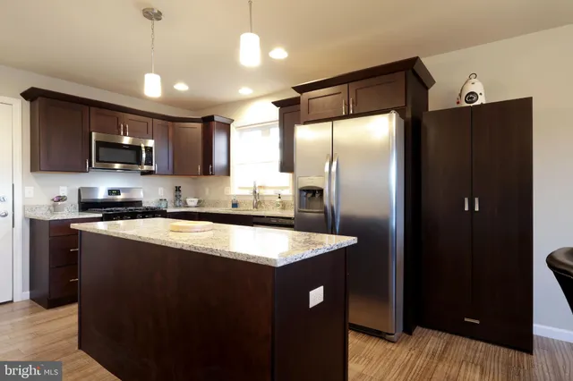 a kitchen with stainless steel appliances granite countertop a refrigerator a sink a stove a microwave and wooden cabinets