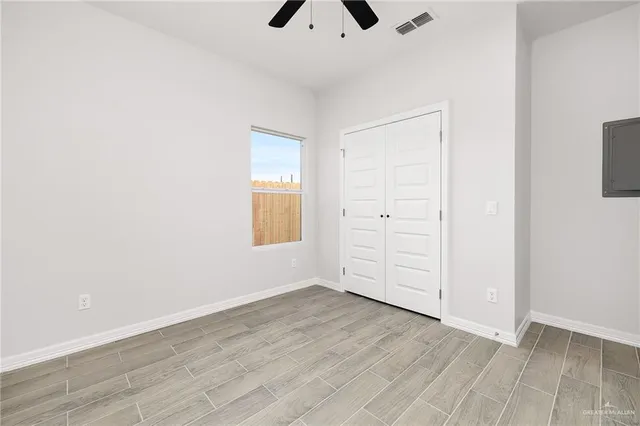 an empty room with wooden floor closet and windows