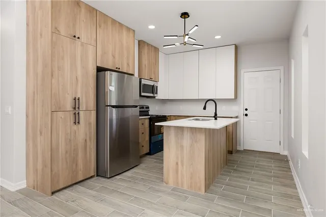a kitchen with kitchen island a sink stainless steel appliances and cabinets