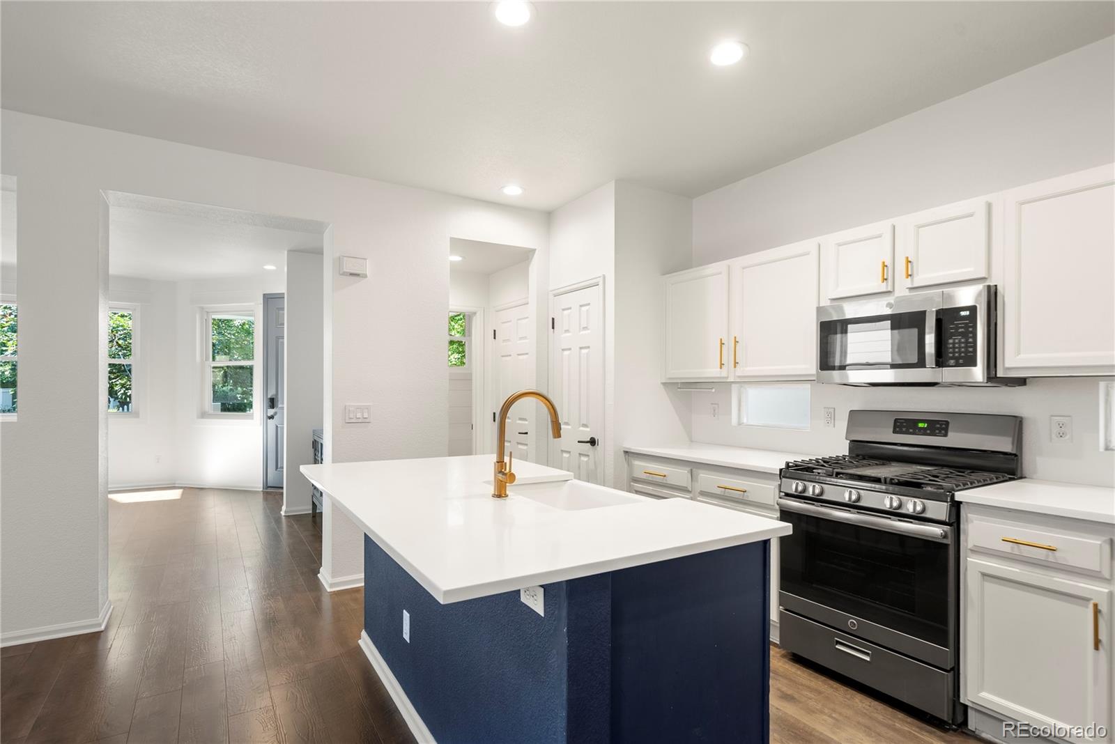 2883 Central Park Boulevard Denver, CO 80238 - Photo 7 of 27 a kitchen with stainless steel appliances a sink dishwasher a stove and a microwave oven with wooden floor