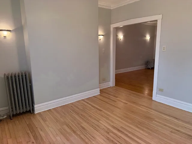 a view of an empty room with wooden floor and a mirror