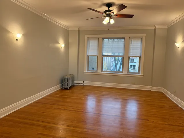 a view of an empty room with window and wooden floor