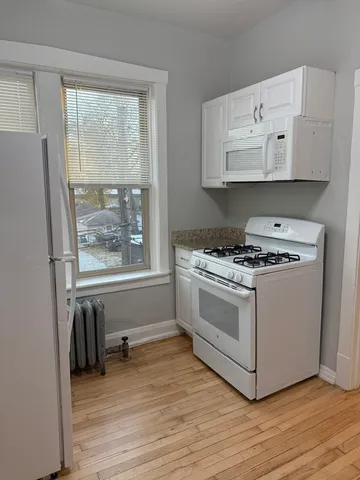 a kitchen with stainless steel appliances white cabinets and wooden floor