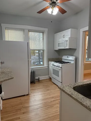 a kitchen with granite countertop a stove a sink and a refrigerator