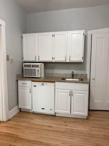 a view of kitchen with granite countertop white cabinets