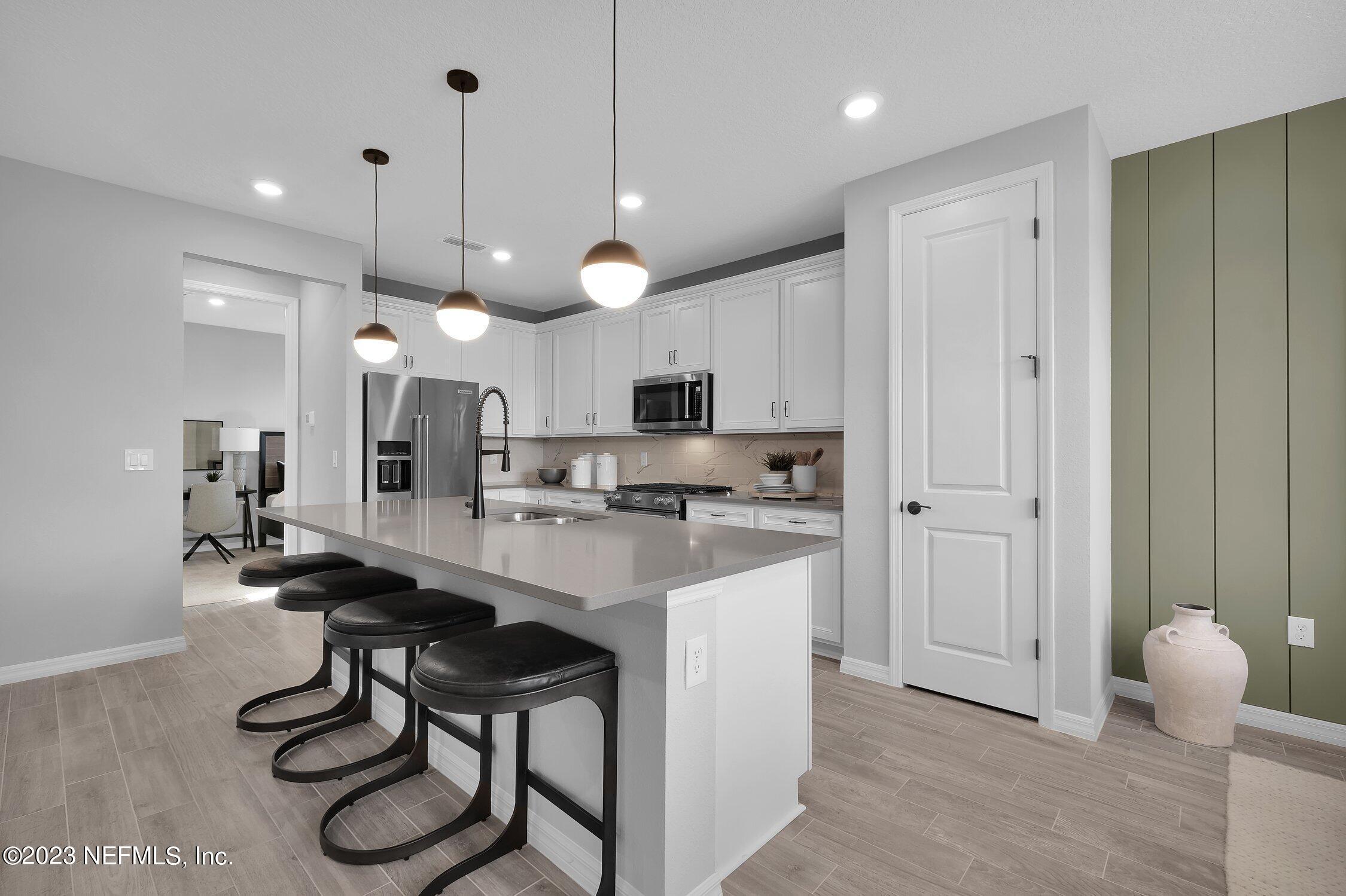 731 Blind Oak Circle St. Augustine, FL 32095 - Photo 9 of 34 a kitchen with stainless steel appliances kitchen island a table chairs refrigerator sink and microwave