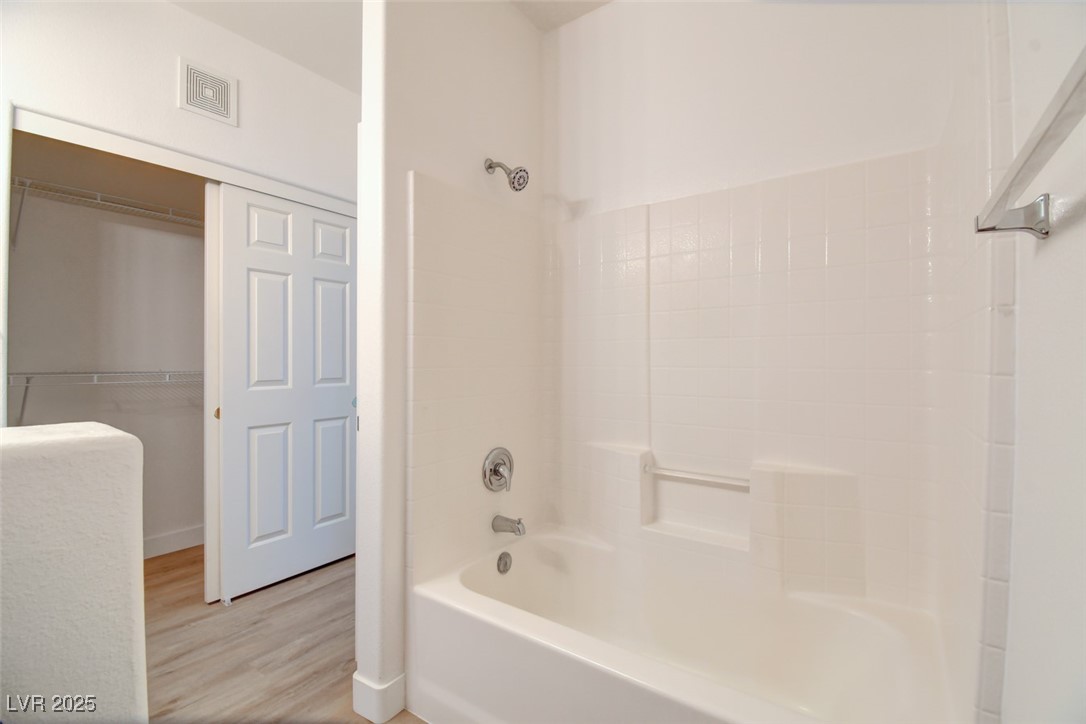 7115 South Durango Drive, Unit 207 Las Vegas, NV 89113 - Photo 16 of 34 Bathroom with washtub / shower combination, a spacious closet, and light wood-style floors