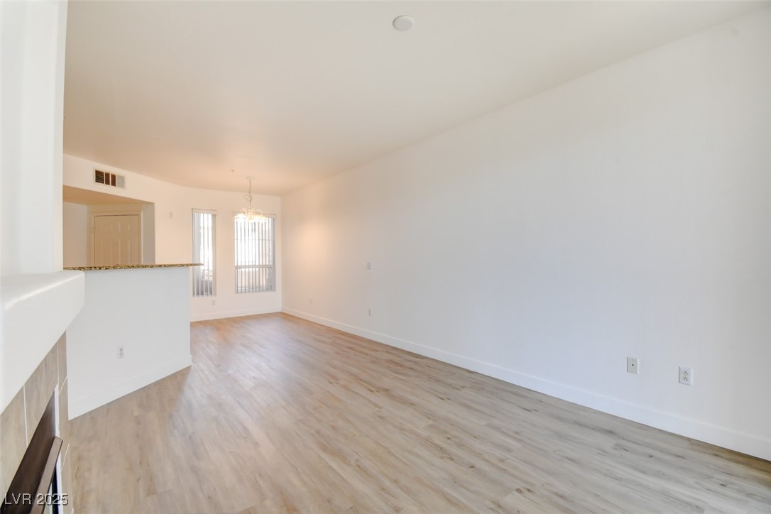 7115 South Durango Drive, Unit 207 Las Vegas, NV 89113 - Photo 7 of 34 Unfurnished living room with a chandelier and light wood-type flooring