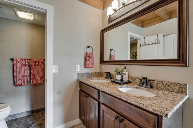 a bathroom with a granite countertop sink mirror vanity and toilet