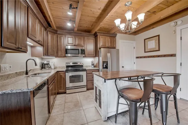 a kitchen with stainless steel appliances granite countertop a table chairs refrigerator and cabinets