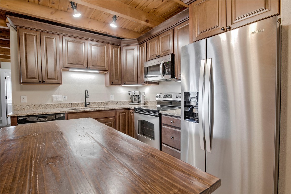 8500 Ryan Gulch Road, Unit G3 Silverthorne, CO 80498 - Photo 9 of 28 a kitchen with stainless steel appliances granite countertop a refrigerator a sink dishwasher a stove and white countertops with wooden floor