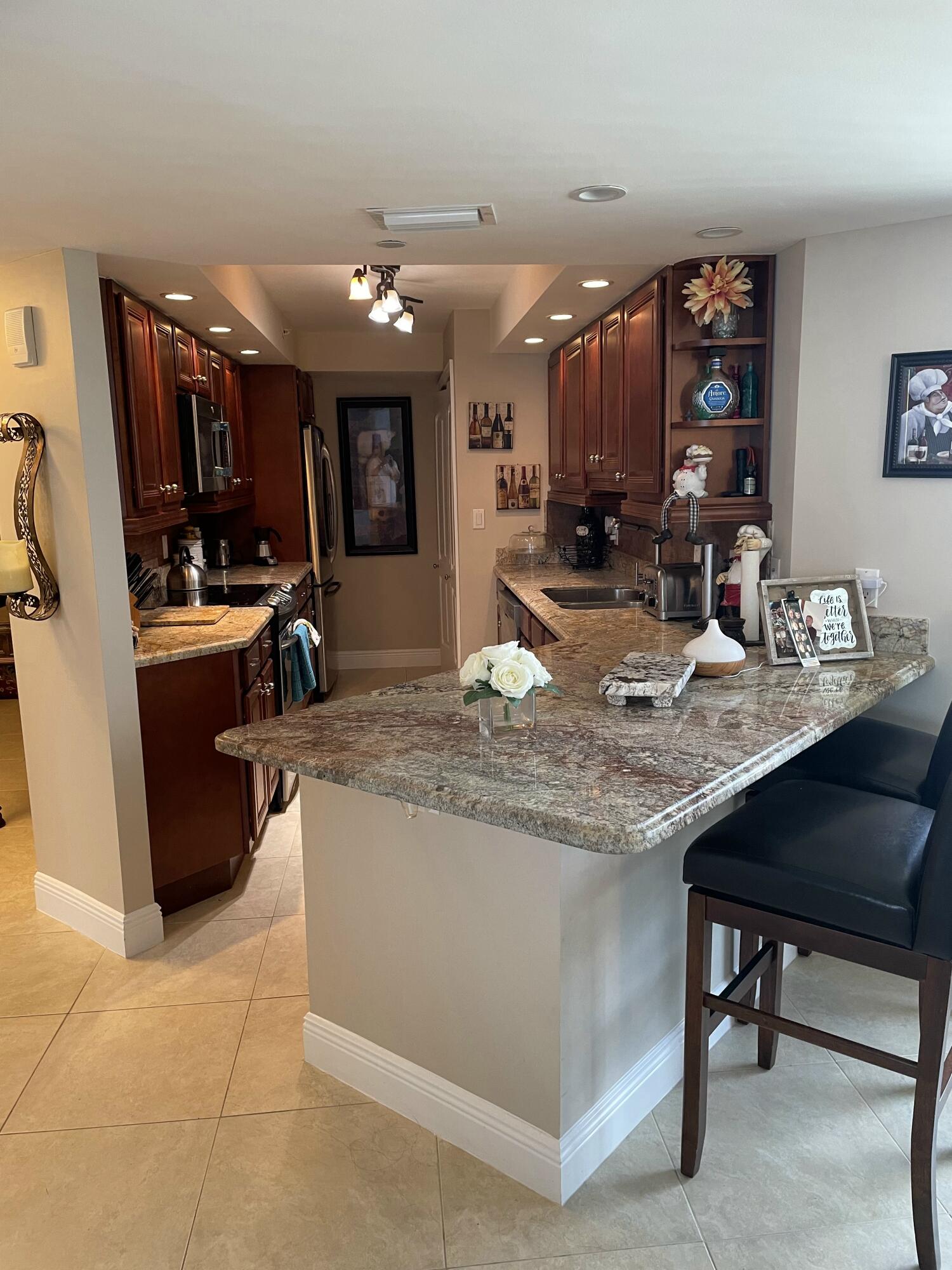 3000 North Ocean Drive, Unit 36C Riviera Beach, FL 33404 - Photo 12 of 18 a kitchen with stainless steel appliances granite countertop a sink a stove and a refrigerator