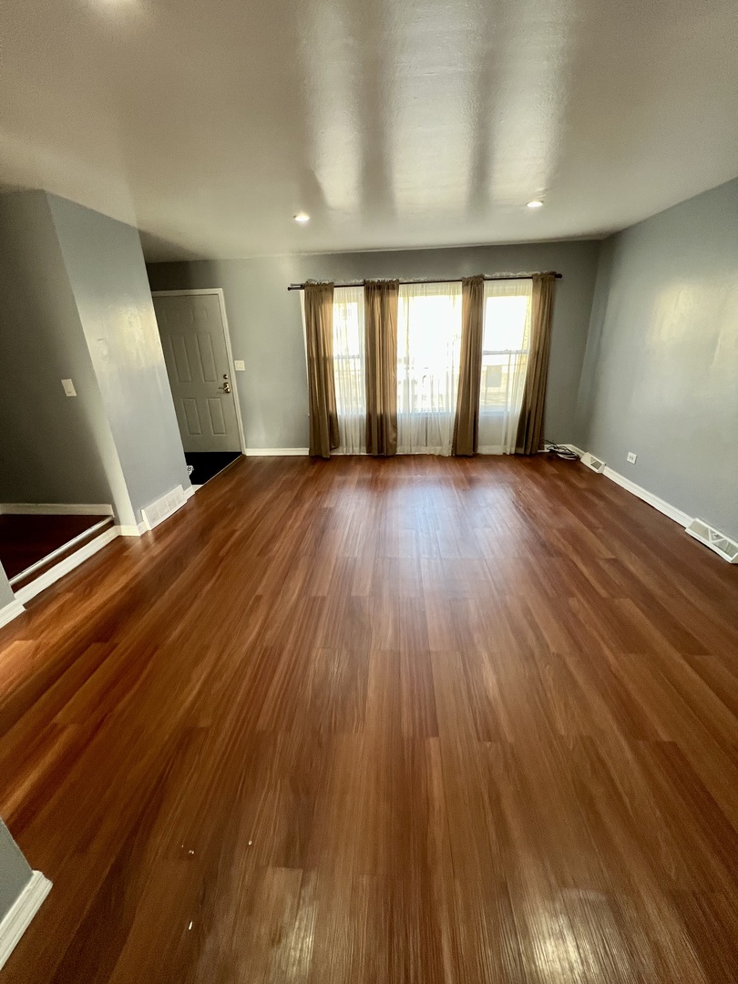 9559 Sumac Road, Unit F Des Plaines, IL 60016 - Photo 4 of 24 a view of an empty room with wooden floor and window