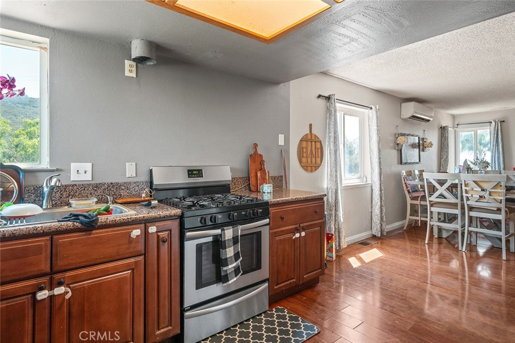 1996 Rainbow Glen Fallbrook, CA 92028 - Photo 27 of 55 a kitchen with stainless steel appliances granite countertop a stove top oven a sink dishwasher and a dining table with wooden floor