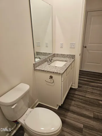 a bathroom with a granite countertop toilet a sink and a mirror