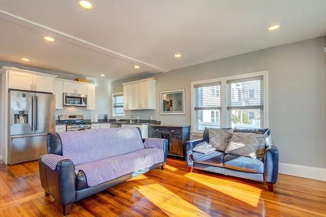 a living room with furniture a wooden floor and kitchen view