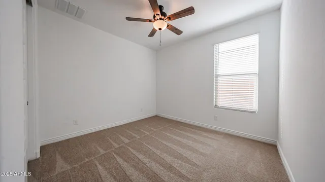 an empty room with a window and a fan