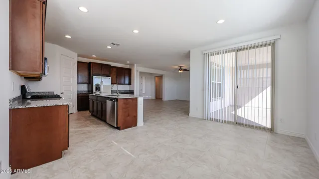 a large kitchen with stainless steel appliances granite countertop a stove top oven a sink and a refrigerator