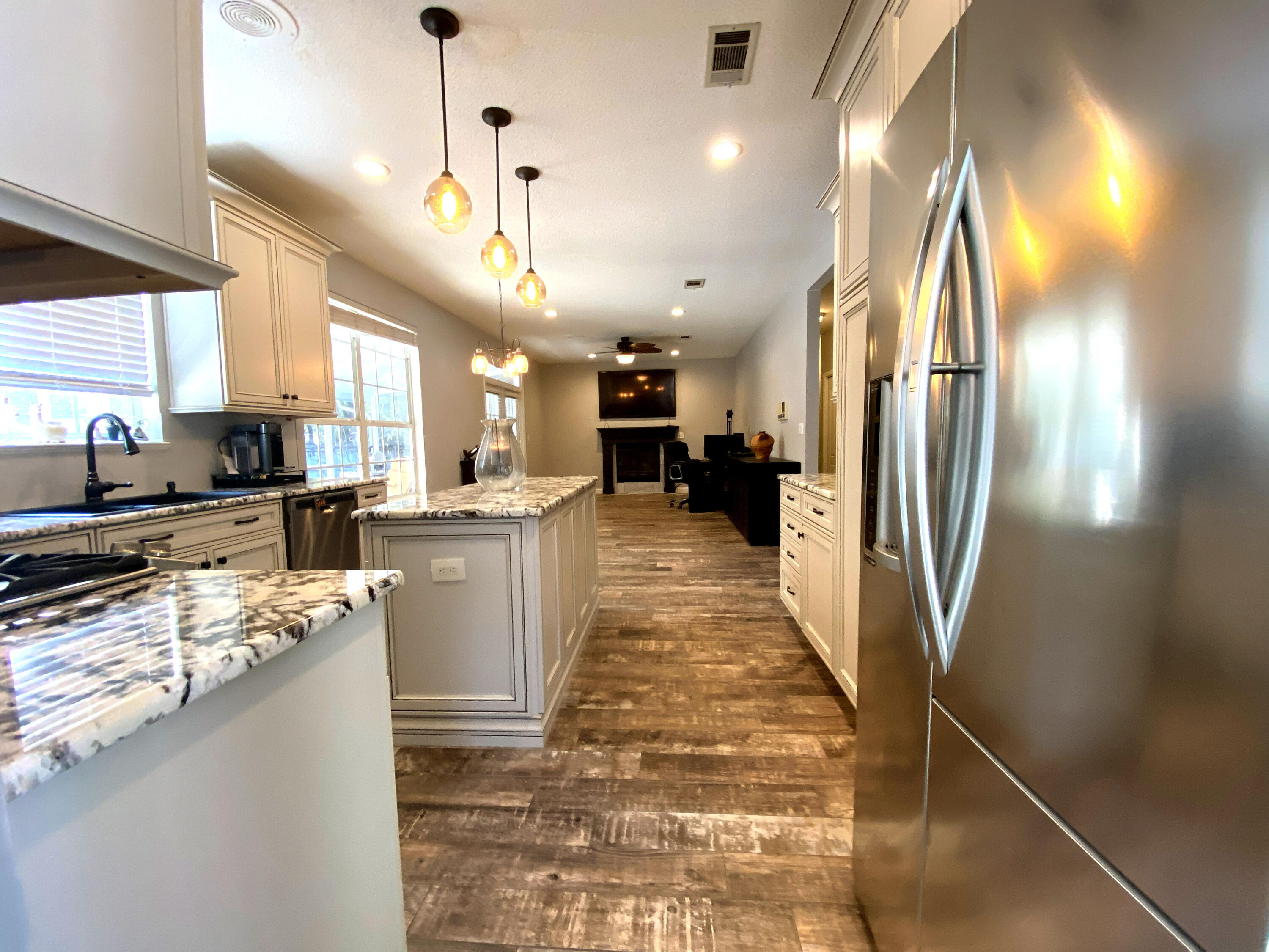 4466 Kingslynn Road Niceville, FL 32578 - Photo 15 of 77 a kitchen with stainless steel appliances granite countertop a refrigerator a sink dishwasher a stove and a dining table with wooden floor