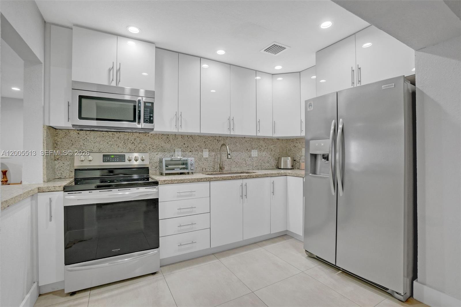 862 West 79th Street Hialeah, FL 33014 - Photo 13 of 34 a kitchen with stainless steel appliances granite countertop a stove a microwave and a refrigerator