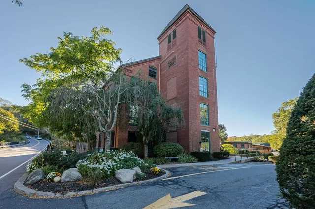 a front view of a multi story residential apartment building with yard and green space