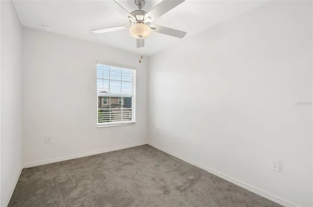 an empty room with a chandelier fan and windows