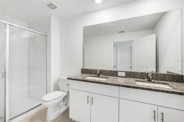 a bathroom with a granite countertop sink toilet and shower