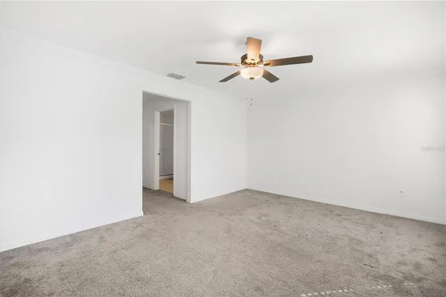 an empty room with a ceiling fan and carpet
