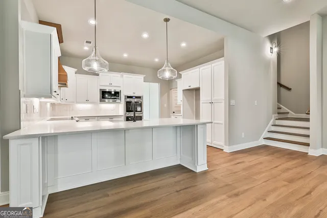 a kitchen with stainless steel appliances kitchen island granite countertop a sink and wooden floor