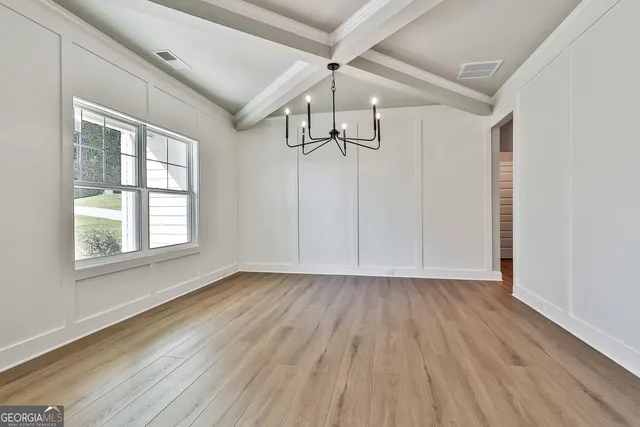 a view of an empty room with wooden floor fridge and a window