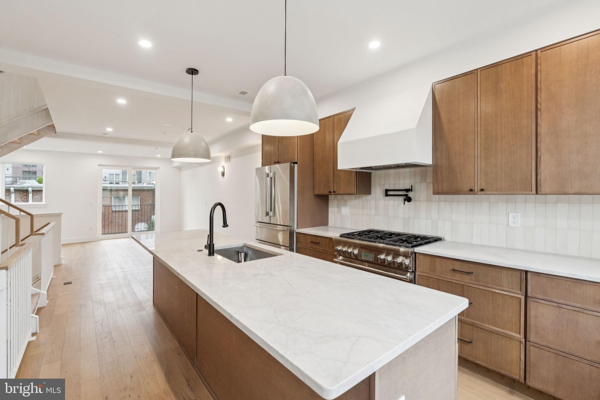 a kitchen with stainless steel appliances a sink a stove a refrigerator and cabinets