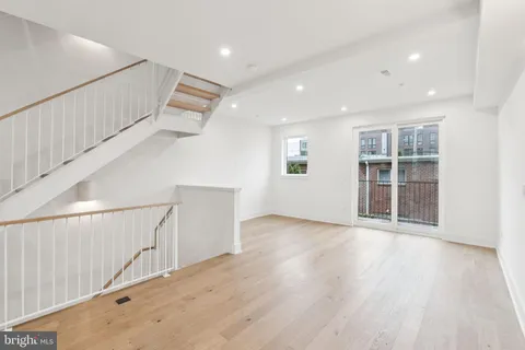 a view of an empty room with wooden floor and stairs