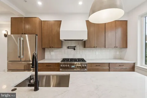 a kitchen with stainless steel appliances granite countertop a refrigerator a stove and a sink