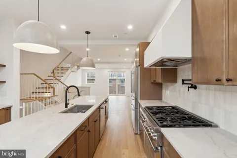 a kitchen with kitchen island a counter space a sink a stove and a refrigerator