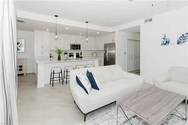 a large white kitchen with a white countertops a stove a dining table and chairs