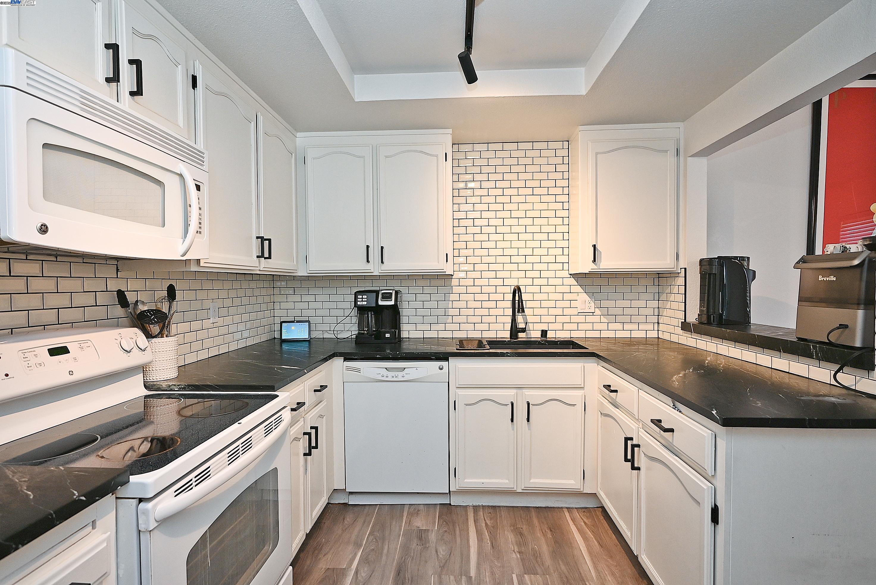 2073 Sand Point Road Discovery Bay, CA 94505 - Photo 23 of 40 a kitchen with a sink dishwasher a stove and white cabinets with wooden floor