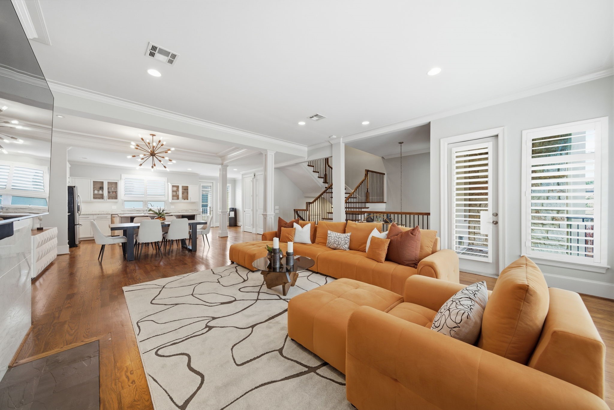 4915 Chenevert Street Houston, TX 77004 - Photo 11 of 41 An inviting open-concept living area seamlessly connects to the dining space and gourmet kitchen, highlighted by beautiful hardwood floors and a statement modern chandelier. Expansive seating, abundant natural light, and balcony access create a warm, contemporary ambiance ideal for gatherings and relaxed everyday living.