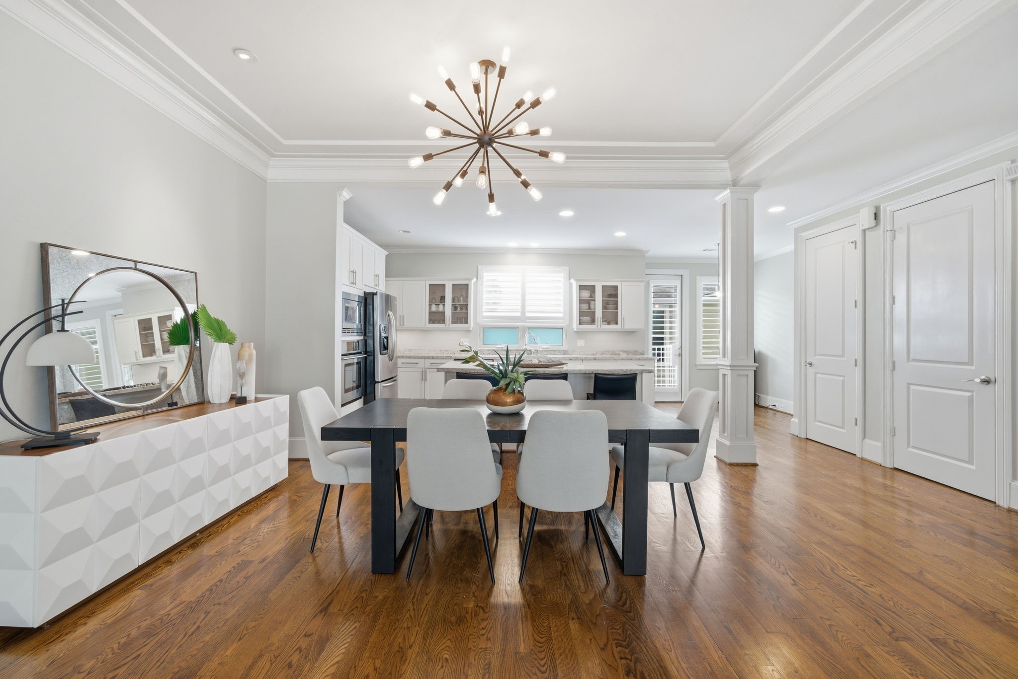 4915 Chenevert Street Houston, TX 77004 - Photo 13 of 41 Sleek hardwood flooring extends through the open dining area, seamlessly connecting to the kitchen. Sophisticated crown molding and a modern designer chandelier elevate the space, while ample natural light and crisp millwork enhance the contemporary feel for effortless gatherings.