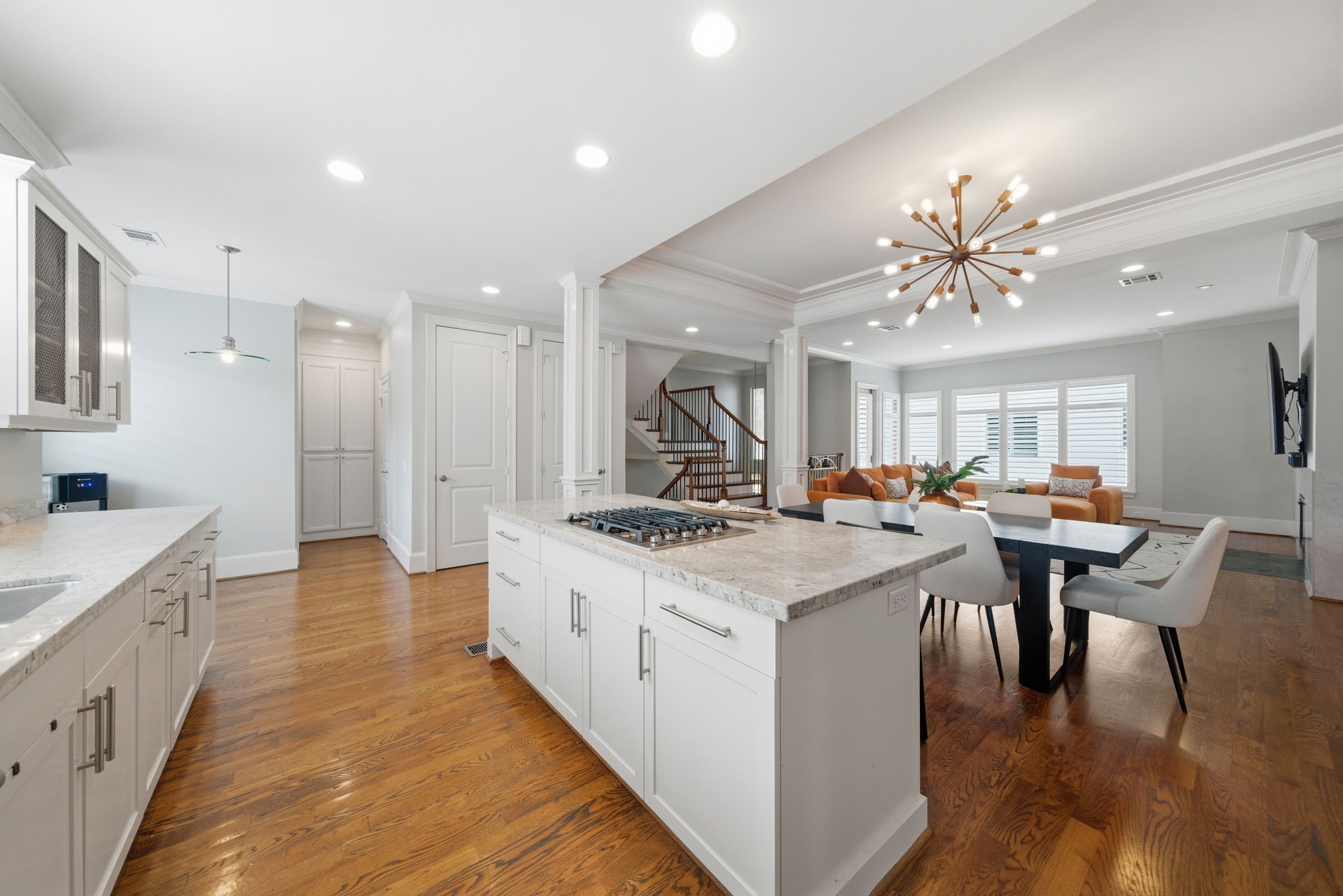 4915 Chenevert Street Houston, TX 77004 - Photo 16 of 41 Expansive open-concept kitchen, dining, and living area highlights contemporary living with wide plank hardwood floors and crisp architectural columns. The oversized island with built-in cooktop, custom cabinetry, and sputnik chandelier create a bright, inviting setting ideal for entertaining or relaxing in style.