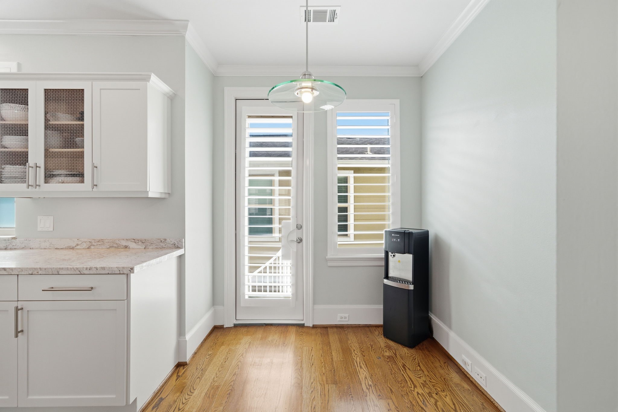 4915 Chenevert Street Houston, TX 77004 - Photo 18 of 41 Sunlit breakfast nook features hardwood flooring and direct access to a private balcony through French doors. Plantation shutters offer privacy while large windows fill the space with natural light, making it a welcoming spot for casual dining or relaxed mornings.
