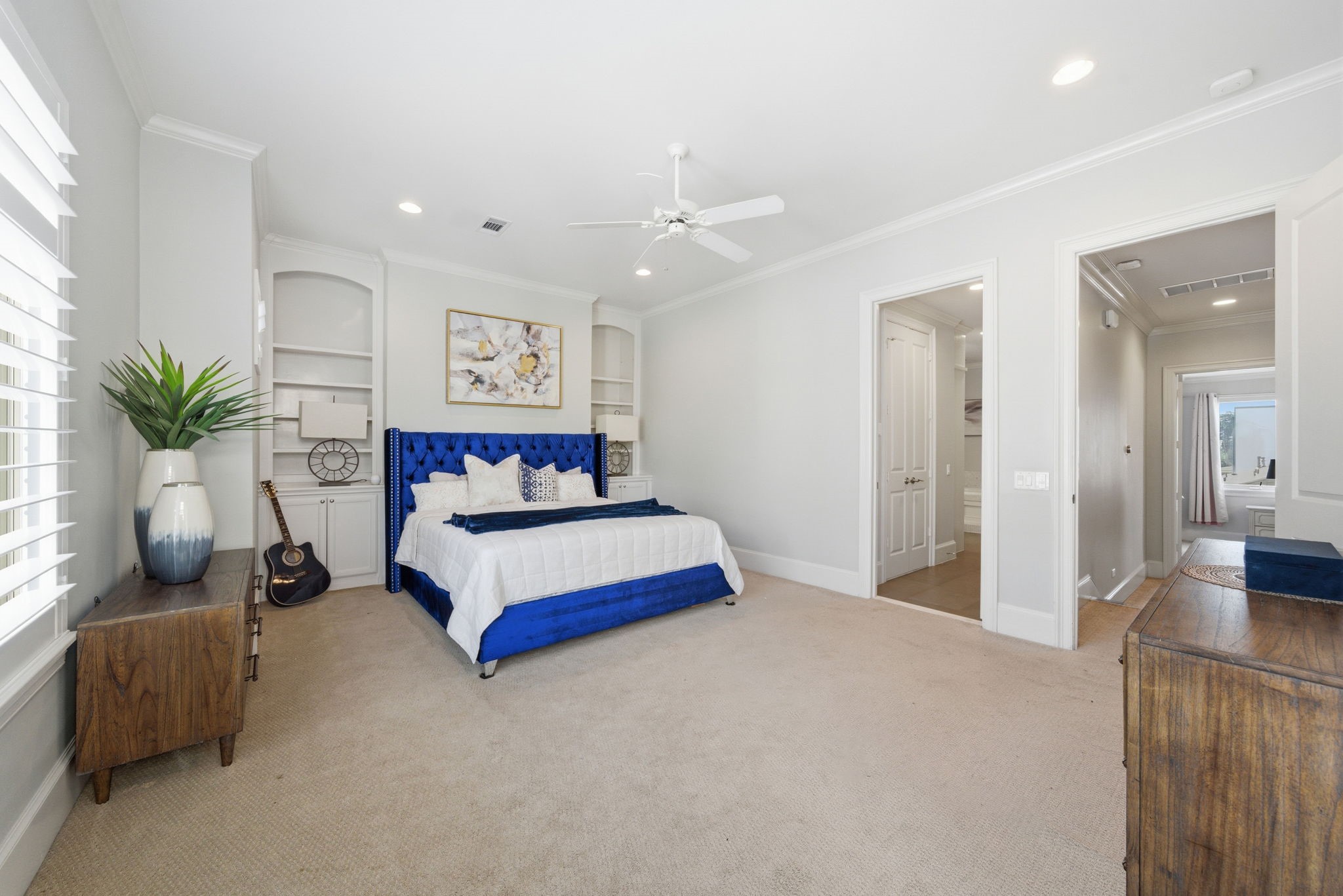 4915 Chenevert Street Houston, TX 77004 - Photo 22 of 41 The spacious primary bedroom features lofty ceilings, a wall of windows with custom shutters, and direct access to a private balcony. Soft carpeting and neutral tones create a tranquil ambiance, while the layout flows seamlessly to the ensuite bath and an oversized walk-in closet.