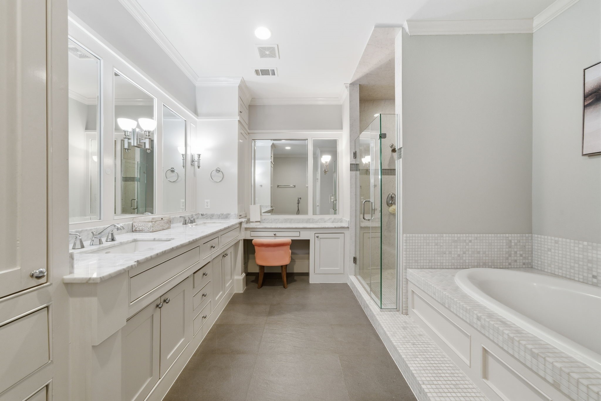 4915 Chenevert Street Houston, TX 77004 - Photo 25 of 41 Dual marble-topped vanities, generous cabinetry, and a dedicated makeup station create a sophisticated oasis in the primary bath. Timeless built-ins and elegant sconces frame the expansive mirrors, blending style and functionality for an effortless daily routine.