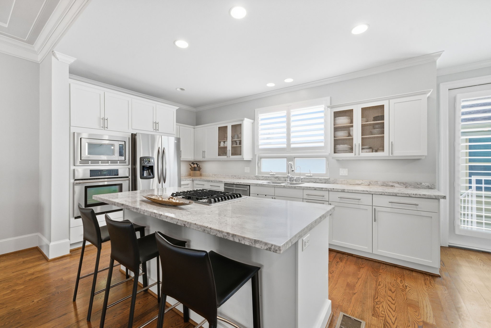 4915 Chenevert Street Houston, TX 77004 - Photo 3 of 41 Enjoy a contemporary kitchen featuring an oversized island with built-in gas cooktop, wide counters for meal prep, and ample storage in custom cabinetry. Stainless steel appliances and abundant natural light create a sleek, functional space ideal for both gourmet cooking and casual dining.