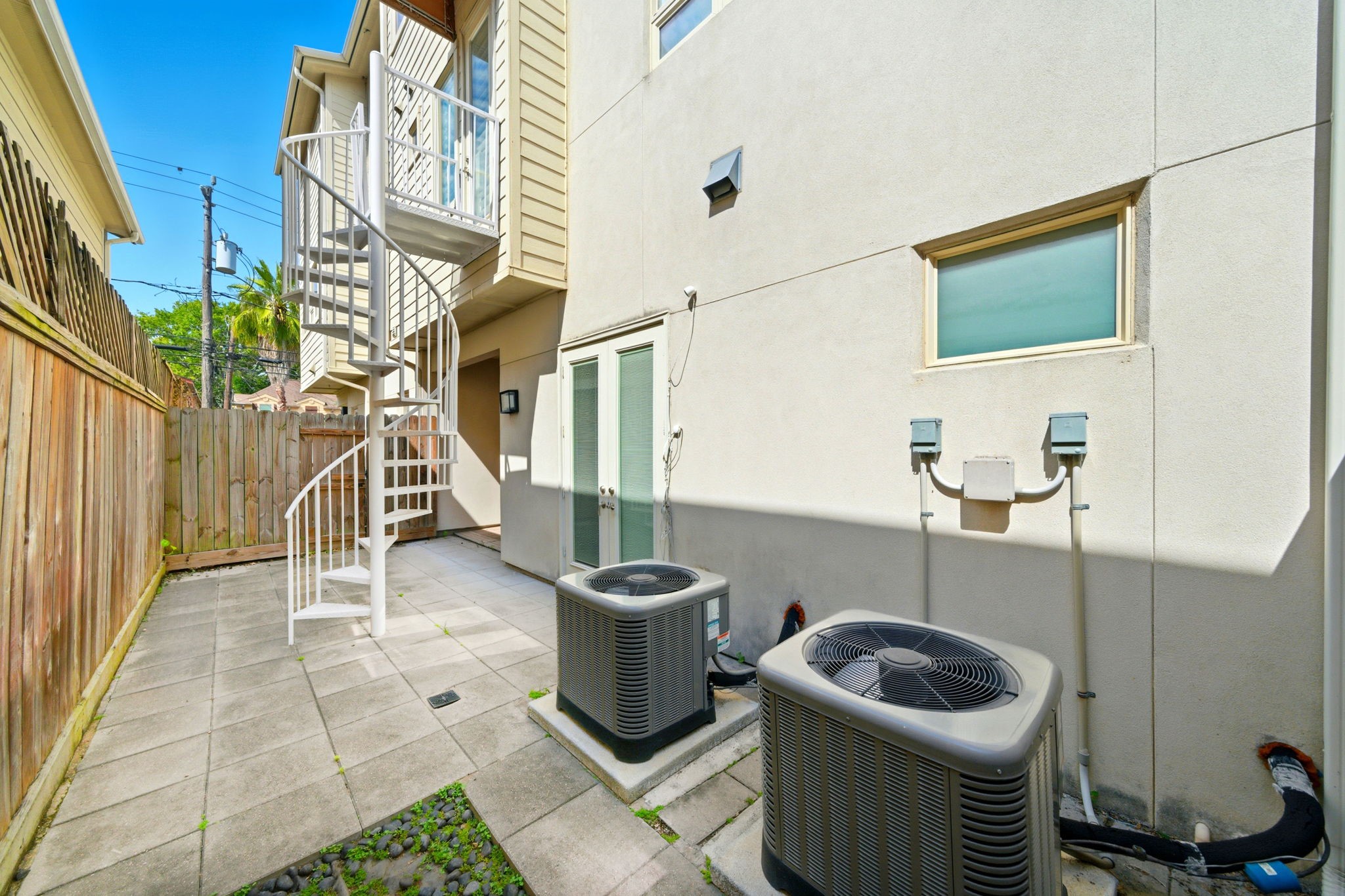 4915 Chenevert Street Houston, TX 77004 - Photo 38 of 41 Discover a versatile, low-maintenance paved patio featuring a modern spiral staircase for easy upper-level access and ample space for outdoor seating or grilling. Fully fenced with direct access to interior living spaces, this private area is ideal for relaxing or practical tasks in the heart of a gated community.